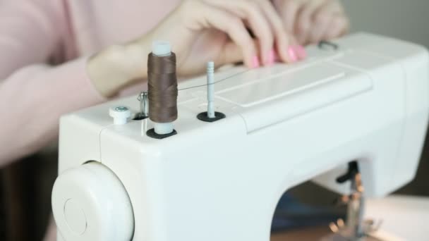 Mujer joven pone un carrete en una máquina de coser, preparándolo para el trabajo . — Vídeos de Stock