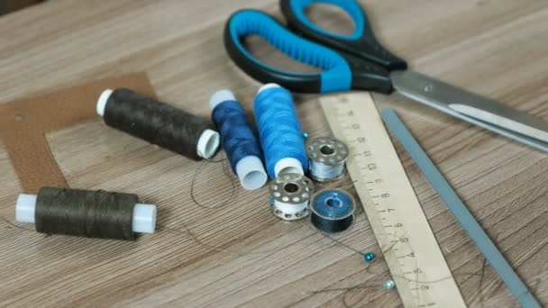 裁縫は、はさみ、糸、ボビン、鉛筆、木製テーブルの上の定規を供給します。. — ストック動画