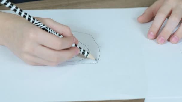 Close-up van de childs handen worden getekend met een eenvoudige potlood op wit papier. Bovenaanzicht. — Stockvideo