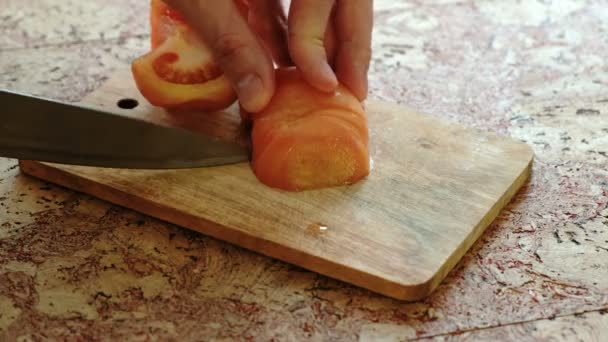 Close-up mans handen snijden van tomaten op een houten bord in keukentafel. — Stockvideo