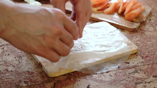 Close-up male hands wrap cutlet and vegetables tomato and Chinese cabbage in rice paper. — Stock Video