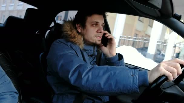 Conducción peligrosa. Un hombre conduciendo un coche, hablando por su celular. Vista lateral . — Vídeo de stock