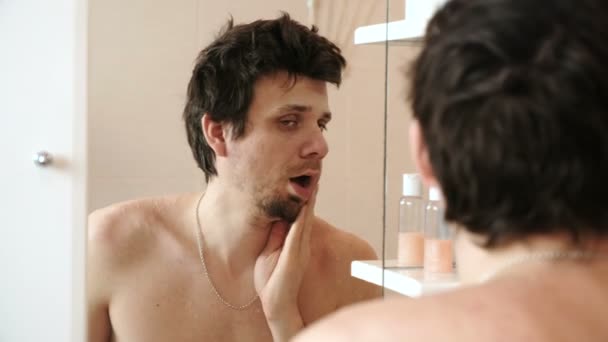 Müder Mann, der gerade aufgewacht ist, als er sein Spiegelbild im Spiegel betrachtet und sich aufrichtet — Stockvideo