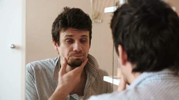 Hombre cansado y somnoliento con resaca que acaba de despertar cepillarse los dientes, mira su reflejo en el espejo . — Vídeos de Stock