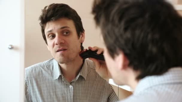Máquina afeitarse el pelo facial. Joven hombre guapo afeitado en seco con trimmer eléctrico . — Vídeo de stock