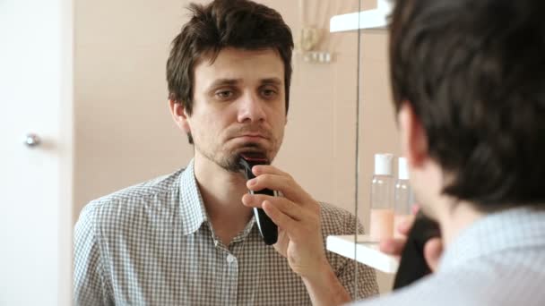 Máquina afeitarse el pelo facial. Joven hombre guapo afeitado en seco con trimmer eléctrico — Vídeos de Stock