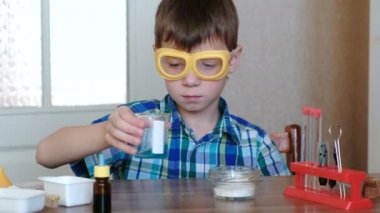 Evde kimya üzerinde deneyler. Çocuklar eller karışımları maddeler ve mavi sıvı kabı içinde.