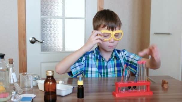 Kísérletek, a kémia otthon. Fiú nézi, cső, hogy megbizonyosodjon arról, a tiszta. — Stock videók