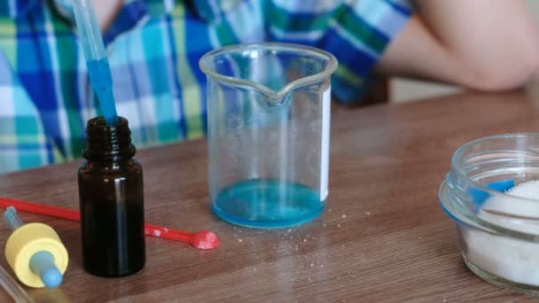 Experimente zur Chemie zu Hause. Nahaufnahme Jungenhände mischen die Substanzen und die blaue Flüssigkeit im Becherglas mit Glasstab. — Stockvideo