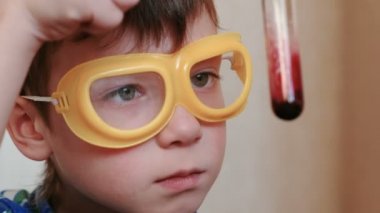 Evde kimya üzerinde deneyler. Tatlı çocuklar yüz test tüpü içeriğini denetler.