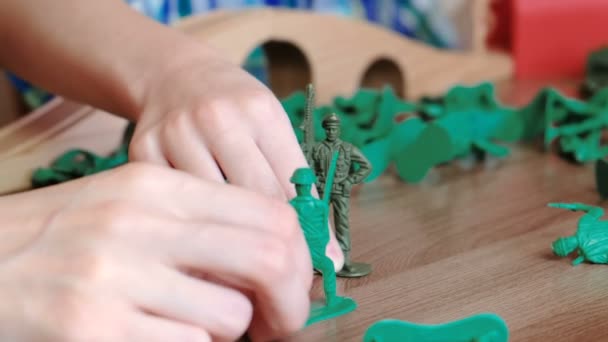 Playing together. Closeup mom and sons hands are playing a plastic soldiers on the table. — Stock Video