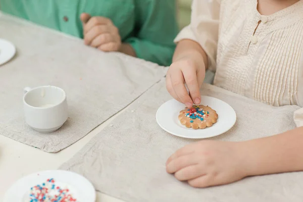Słodkie dzieci ozdabiają cookies przy stole w kuchni — Zdjęcie stockowe