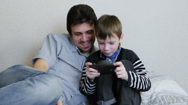 Vader en zoon samenspelen spel in de mobiele telefoon. — Stockvideo