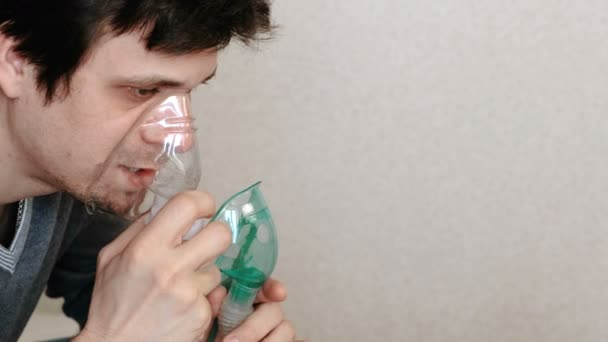 Använda nebulisatorn och inhalator för behandling. Ung man andas in genom inhalatorn mask. Sidovy. — Stockvideo