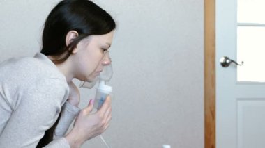 Nebulizatör ve astım tedavisi için kullanın. Genç kadın inhaler maskesi teneffüs edilmesi. Yan görünüm.