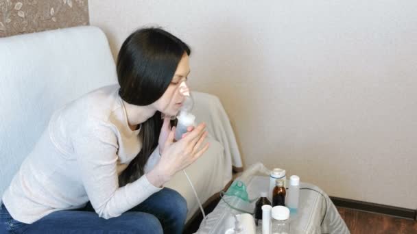 Use nebulizador e inhalador para el tratamiento. Mujer joven inhalando a través de la máscara del inhalador. Vista lateral . — Vídeo de stock