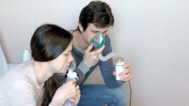 Χρησιμοποιούν νεφελοποιητή και συσκευή εισπνοής για τη θεραπεία. Άνδρας και γυναίκα εισπνοή μέσω της συσκευής εισπνοής μάσκα. Πλάγια όψη. — Αρχείο Βίντεο