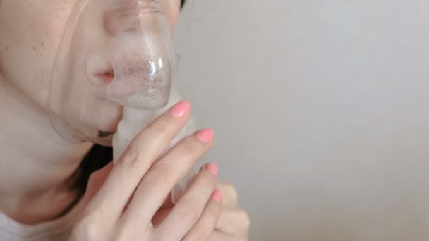 Använda nebulisatorn och inhalator för behandling. Närbild mask på kvinnans ansikte andas in genom inhalatorn mask. Framifrån. — Stockvideo