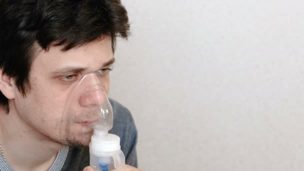 Use nebulizador e inhalador para el tratamiento. Hombre joven inhalando a través de la máscara del inhalador. Vista lateral . — Vídeos de Stock