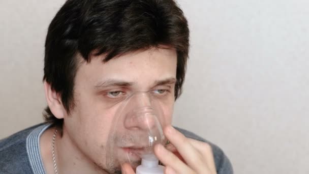 Use nebulizador e inhalador para el tratamiento. Hombre joven inhalando a través de la máscara del inhalador. Vista lateral . — Vídeo de stock