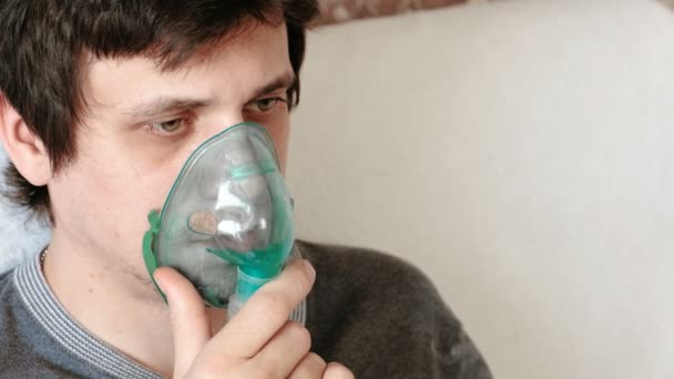 Use nebulizer and inhaler for the treatment. Closeup mans face inhaling through inhaler mask. Front view. — Stock Video