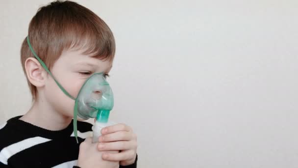 治療のためには、ネブライザーと吸入器を使用します。吸入マスクを通して吸い込むことの男の子。横から見た図. — ストック動画