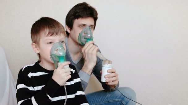 Använda nebulisatorn och inhalator för behandling. Mannen och pojken som andas in genom inhalatorn mask. Sidovy. — Stockvideo