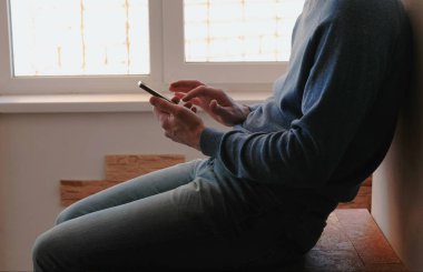 Telefon olan adam. Tanınmayan genç adam içinde hareket eden telefon pencerenin yakınındaki balkonda oturmuş sohbet