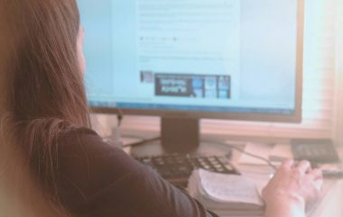 Bilgisayar üzerinde çalışıyor. İnternet sayfalarında ekran tarama tanınmaz halde genç bir kadın. Arkadan Görünüm.