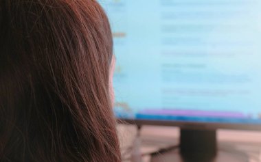 Bilgisayar üzerinde çalışıyor. Tanınmayan genç kadın internet tarama ekranında sayfaları ve online mağazada alışveriş yapar. Arkadan Görünüm.