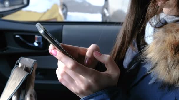 Vrouw in een auto met een mobiele telefoon. Closeup dames handen chatten in telefoon. — Stockvideo