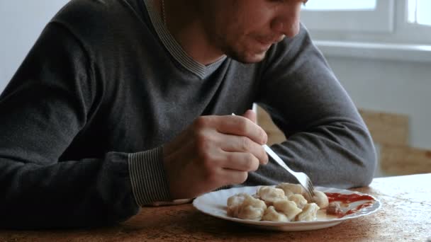 Ο άνθρωπος τρώει dumplings με ένα πιρούνι, τοποθέτησή τους σε σάλτσα ντομάτας στην κουζίνα — Αρχείο Βίντεο