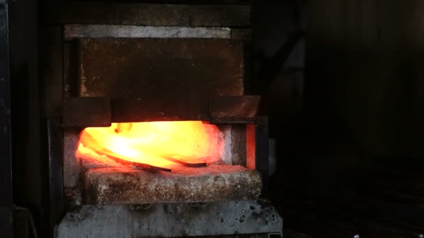 Haciendo la espada de metal en la fragua. Calentamiento de palanquillas metálicas en el horno . — Vídeos de Stock