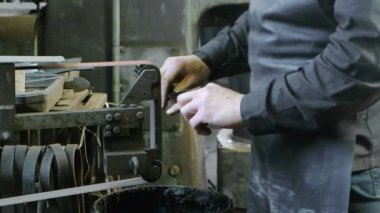 Metal kemer-kabuğu bir makinede demir çubuklar taşlama. Yakın çekim, bir el mans.