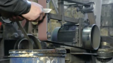 Demir çubuklar bir kemer-kabuğu makine üzerinde metal bıçak bileme. Yakın çekim, bir adamın elleri.