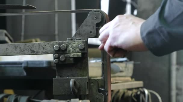 Molienda de palanquillas de metal en una máquina de molienda de correa. Primer plano de una mano de hombre . — Vídeos de Stock