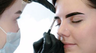 Güzellik uzmanı istemcileri kaşları fırça ile boya koyar. Closeup Önden Görünüm. Kaş düzeltme.