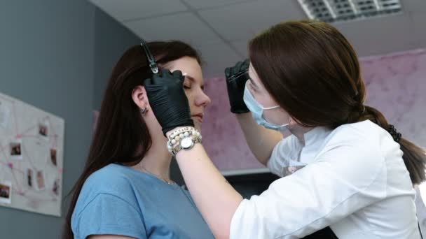 Cosmetologist executa o procedimento da sobrancelha da correção com pinças. Vista lateral para cima. Correção da sobrancelha . — Vídeo de Stock