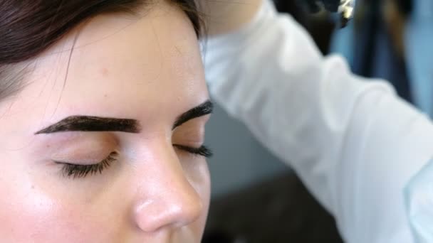 美容师用刷子把油漆涂在客户的眉毛上。特写眼睛的看法。眉矫正. — 图库视频影像