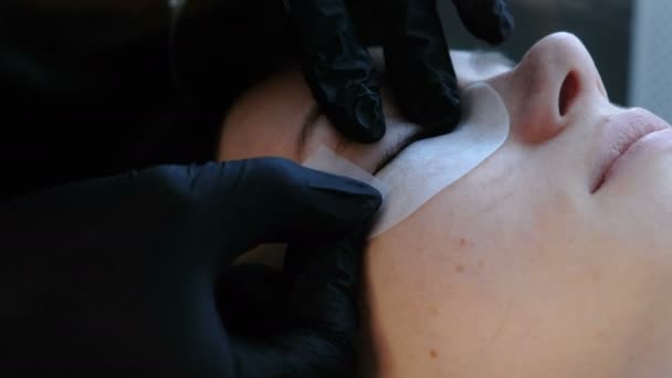 Лікування краси. Косметолог прикріплює ліфчики для вії до повік жінок . — стокове відео