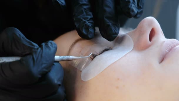 Kosmetolog separerar fransarna med en nål och böjer dem i papiljotter. Botox och lash laminering. — Stockvideo