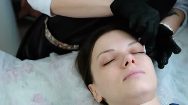 Kosmetikerin reibt den Klienten die Augenlider mit einem Wattepad ein. Botox und Peitsche Laminierung. Schönheitsbehandlung. — Stockvideo