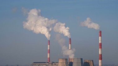 Gökyüzü arka plan duman ile üç kırmızı ve beyaz borularla termik Santrali.