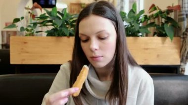 Genç esmer kadın taze yemek yeme peynir değnek bir kafede kızarmış. Önden Görünüm.