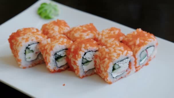 Rolos close-up com caviar com gengibre em conserva e wasabi em uma placa retangular branca . — Vídeo de Stock