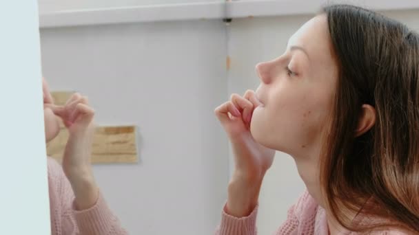 Mladá žena zkoumá a při pohledu na její zuby před zrcadlem. Detail obličeje. — Stock video
