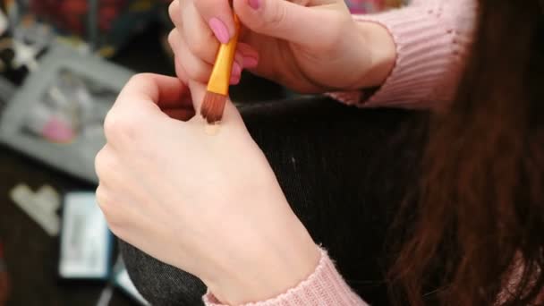 Closeup dames handen zetten de tonale crème op het gezicht met borstel om te doen een make-up voor de spiegel. — Stockvideo