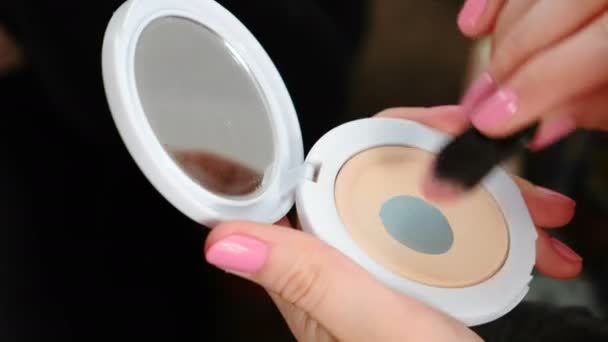 Primeros planos de las manos de las mujeres con polvo cosmético y espejo haciendo un maquillaje con un cepillo . — Vídeo de stock