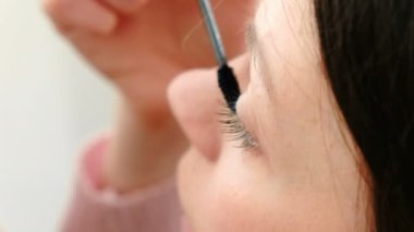 Genç güzel kadın gözleri maskara ile boyar. Closeup göz, üstten görünüm.