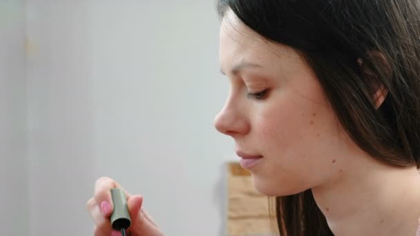 Mulher remove o excesso de rímel do pincel para pintar os olhos . — Vídeo de Stock